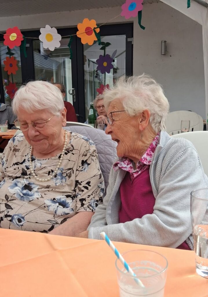 Zwei Bewohnerinnen sitzen beim Sommerfest zusammen